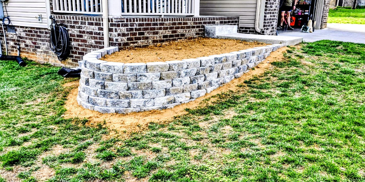 Curved stacked-block retaining wall along the front of a home